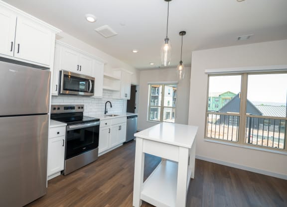 a large kitchen with white cabinets and stainless steel appliances at The Crossings  at Windsong, Prescott Valley, AZ