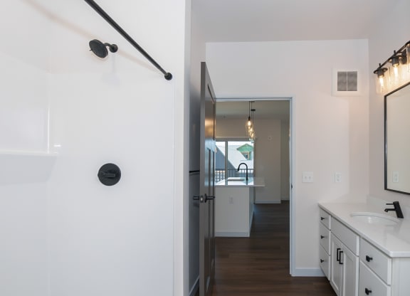 a bathroom with a sink and a shower and a hallway with a door at The Crossings  at Windsong, Arizona, 86314