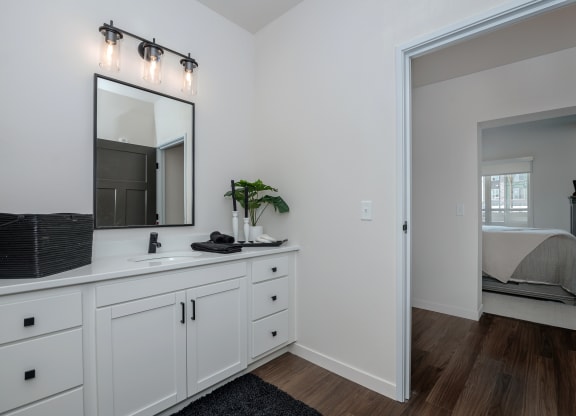 a bathroom with white cabinets and a mirror and a bedroom with a bed at The Crossings  at Windsong, Arizona