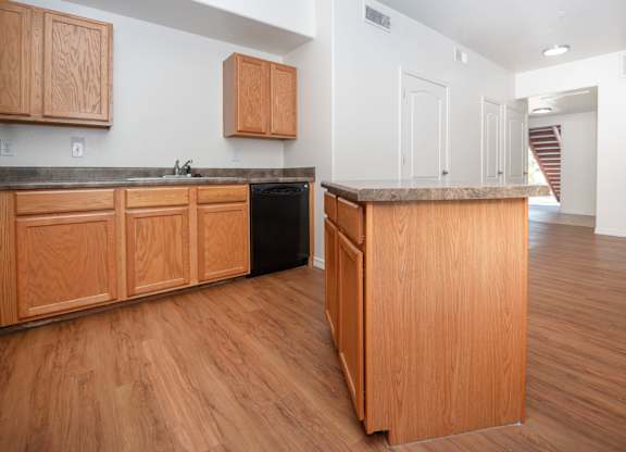A kitchen with wooden cabinets and a black dishwasher.
