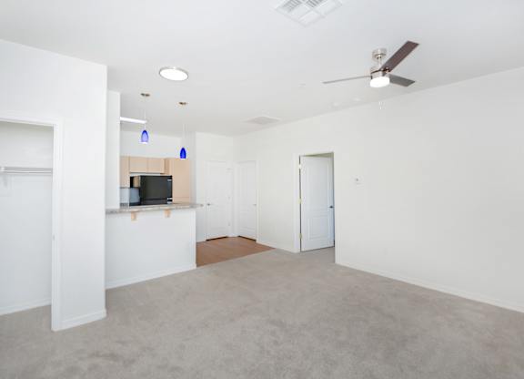 A spacious room with a ceiling fan and a flat screen TV mounted on the wall.