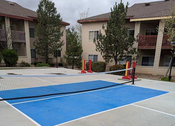 A blue and white tennis court with orange cones around it.