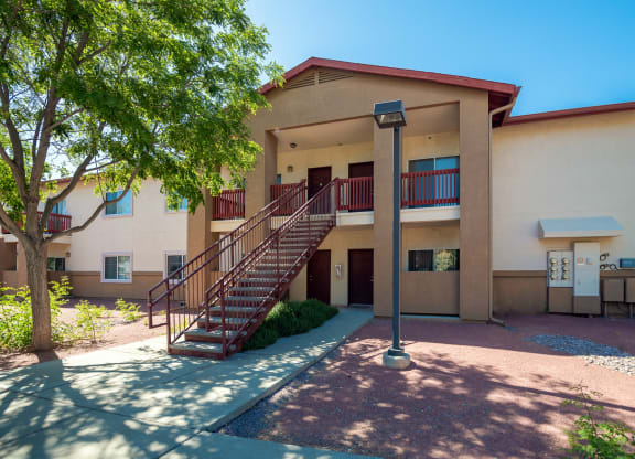 a building with a staircase and a tree in front of it