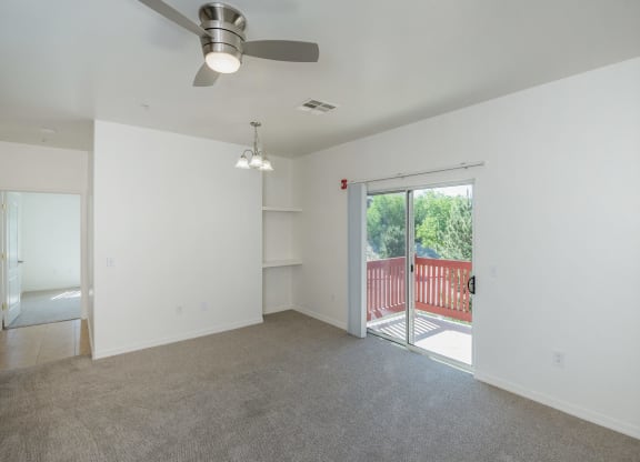 an empty living room with a sliding glass door to a balcony