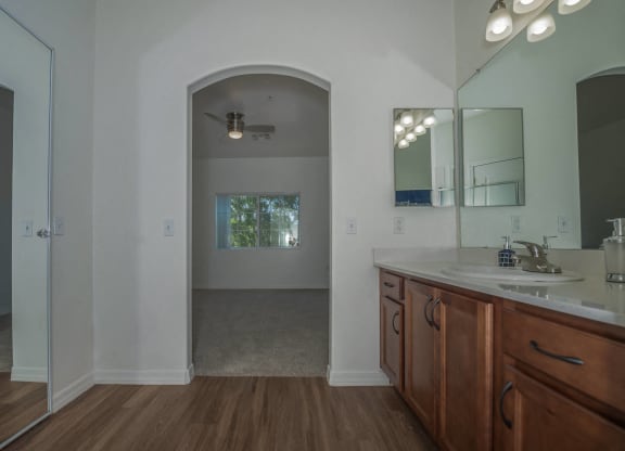 a bathroom with a sink and a mirror and a door into a room with a