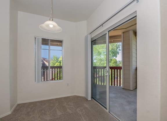 an empty living room with a sliding glass door to a balcony