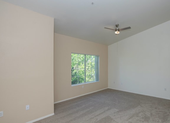 an empty room with a window and a ceiling fan