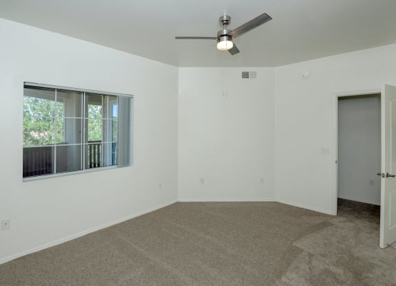 an empty room with a window and a ceiling fan