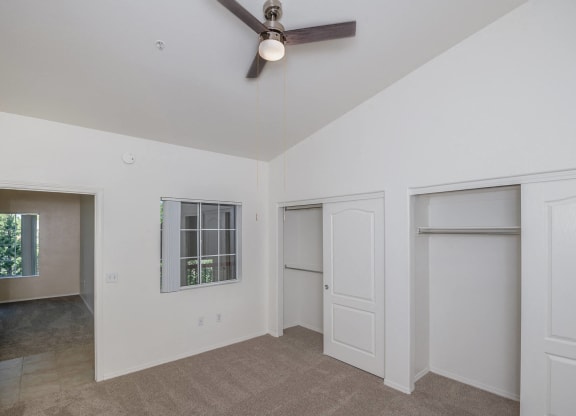 a living room with white walls and a ceiling fan