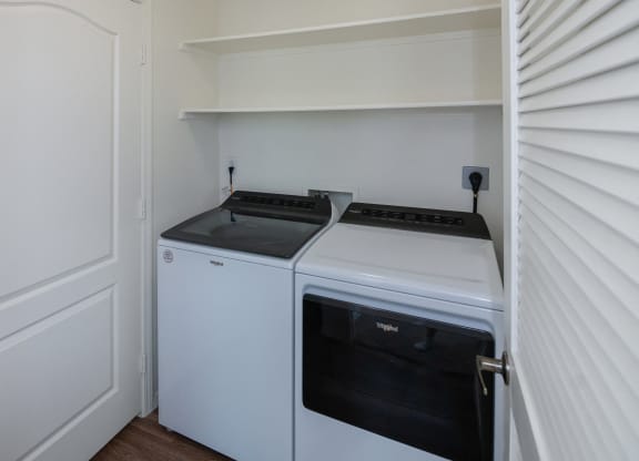 a white washer and dryer in a small room with a white door