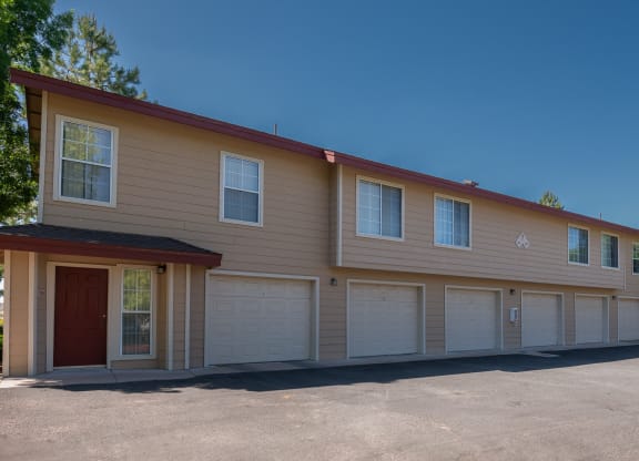 the front of a tan building with white garage doors