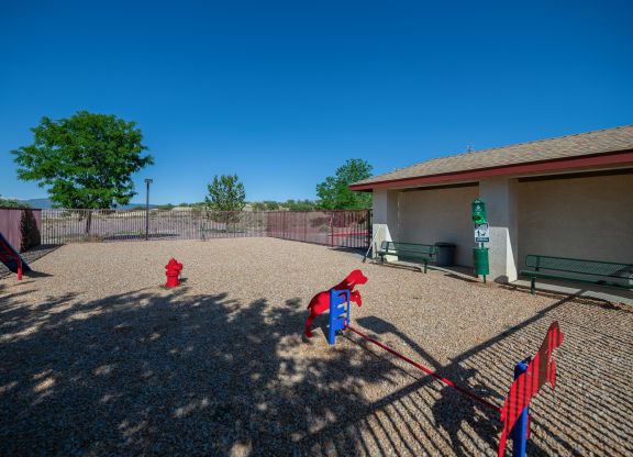 two red fire hydrants in a fenced in play area with a building