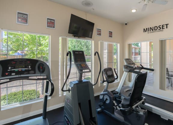 a gym with exercise machines and a tv