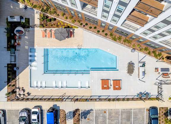An aerial view of a pool surrounded by chairs and umbrellas.