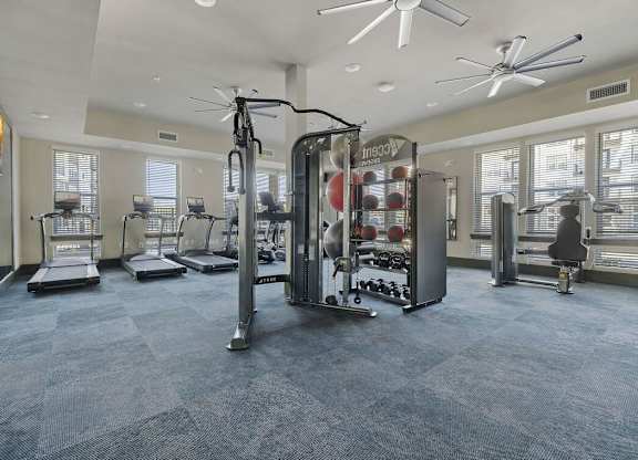 A gym with a variety of equipment including treadmills, weights, and a squat rack.