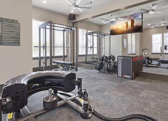 A gym with a weight bench, a fan, and a television.