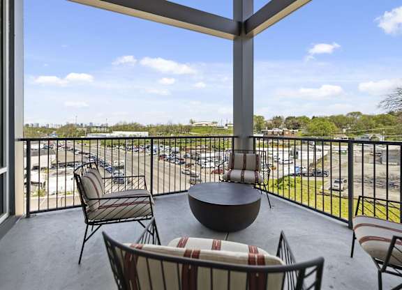 A patio with a table and chairs overlooking a parking lot.
