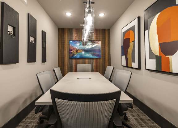 A conference room with a long table and chairs, a chandelier, and framed artwork on the walls.