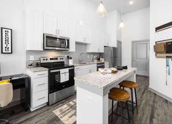 A modern kitchen with a white island and stainless steel appliances.