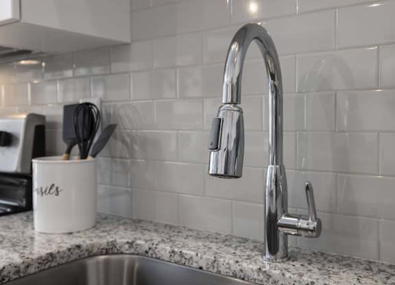 A kitchen sink with a chrome faucet and a mug with the word