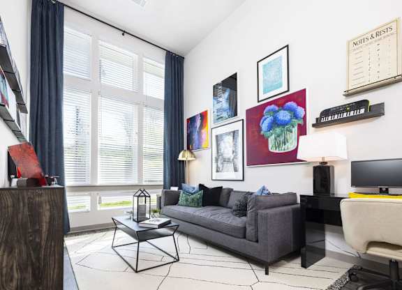 A living room with a grey couch, a coffee table, and a painting on the wall.