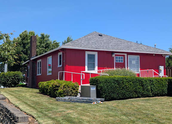 A red house with a grey roof and a chimney.