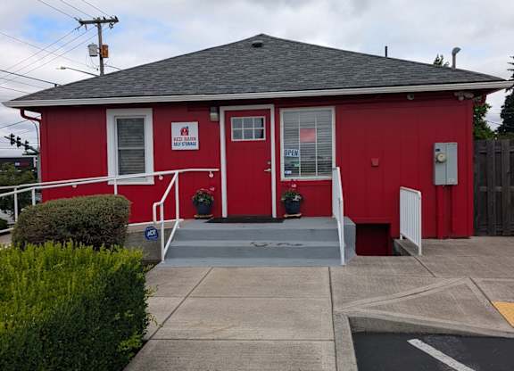 A red building with a grey roof and a sign on the front.
