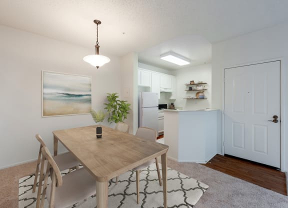 Ventura, CA Apartments - Cypress Meadows - Dining Area with a Hanging Light Fixture, Wooden Table, and an Area Rug