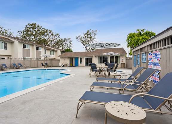 A pool with sun loungers and a building in the background.