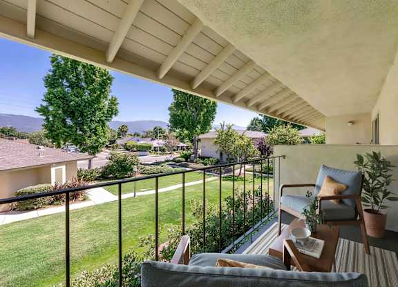 A balcony with a chair and a table with a plant on it.