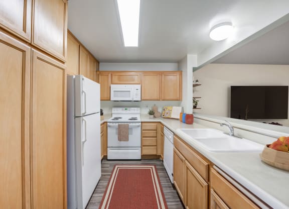 Apartments for Rent in Goleta, CA - Encina Meadows - Kitchen with Plank Flooring, Wood-Tone Cabinetry, Efficient Appliances, and Breakfast Bar.