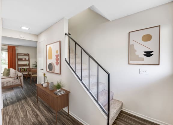 a bedroom with a staircase and a living room in the background