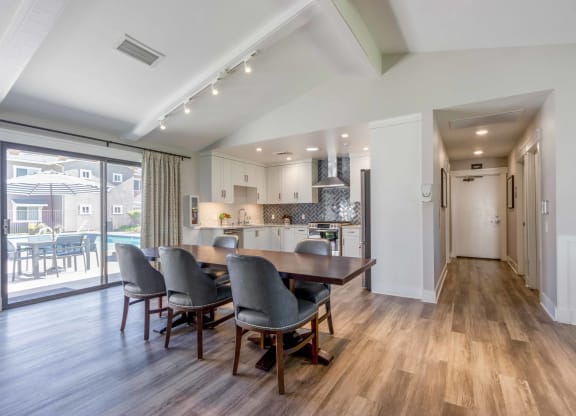 a dining room with a table and chairs in front of a kitchen with a door