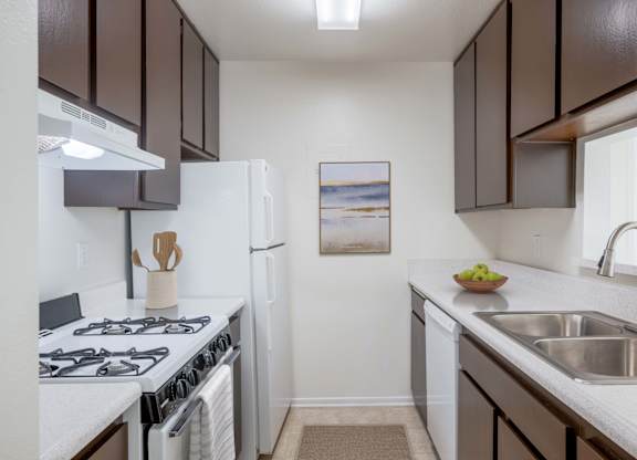 A kitchen with white and brown cabinets, a white stove, and a white refrigerator.