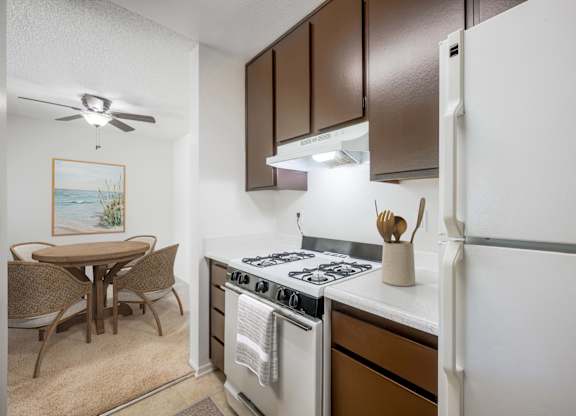 A kitchen with a stove, refrigerator, and dining table.
