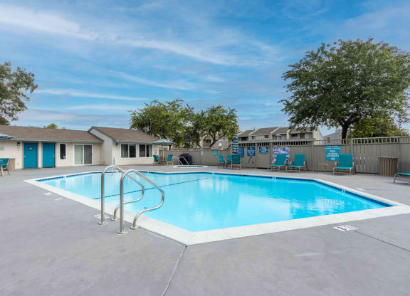 our resort style swimming pool is next to our apartments with a fence and trees
