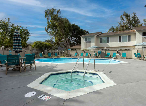Lompoc, CA, Apartments Near Vandenberg Airport Base - Oceanwood - Gated Pool with Hot Tub, Lounge Seats, Tables, Chairs, and Umbrellas.