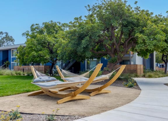 One-Bedroom Apartments In Goleta, CA - Patterson Place - Free-Standing Hammocks Surrounded By Concrete Walking Path, Manicured Lawn, And Trees.