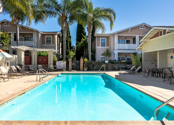 2-Bedroom Apartments in Ventura, CA - Ralston Courtyards - Pool With Spacious Sundeck, Lounge Chairs, Umbrellas, And Palm Trees.