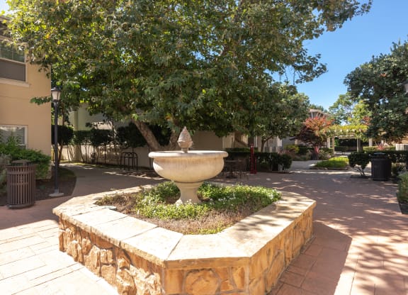 a fountain in the middle of a courtyard with a tree