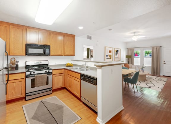 Ventura, CA Apartments - Ralston Courtyards - Kitchen With Plank Flooring, Stainless-Steel Appliances, And Custom Wood Cabinets.