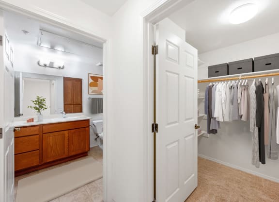 a bathroom with a white door and a closet full of clothes