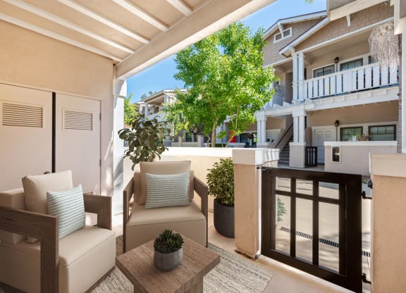 a patio with chairs and a table and a balcony