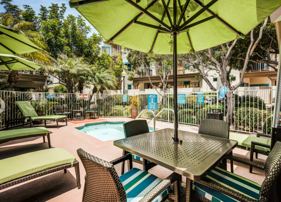 a patio with a table and chairs and a pool in the background