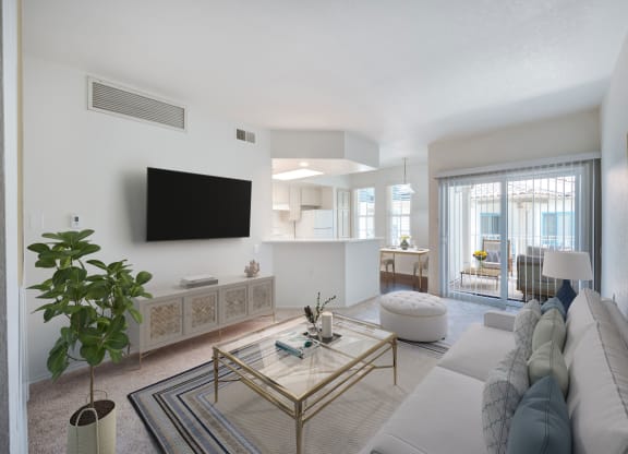 2-Bedroom Apartments in Santa Barbara, CA - Rancho Franciscan - Living Room With Carpeting, Couch, Swivel Stool, Glass-Top Coffee Table, Mounted TV, and Sliding Glass Door with Access to Patio