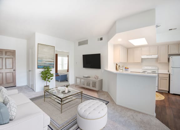 a living room and kitchen with white walls and wood floors