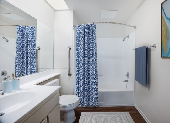 a bathroom with a white sink and toilet and a white shower with a blue shower curtain
