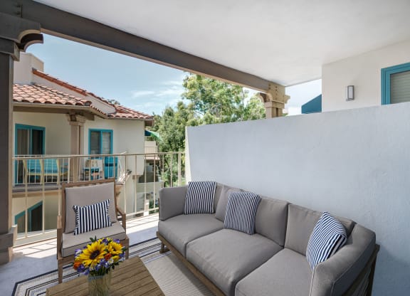 a couch on a balcony with a vase of flowers