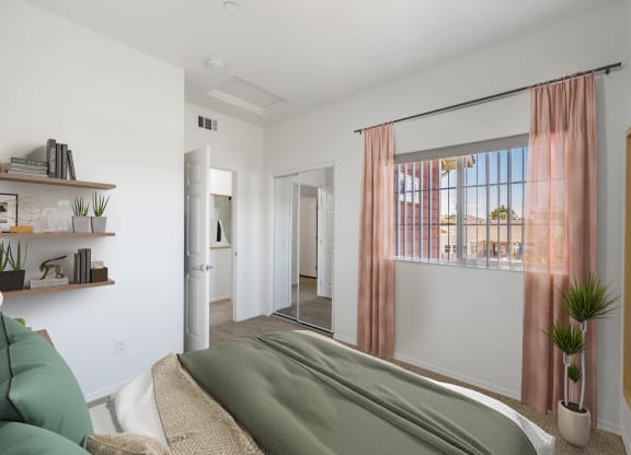 Santa Maria, CA, Apartments Near Target - Siena - Bedroom with Carpeted Floor, Bed, Floating Shelves with Books and Decors, Mirrored Closet, and Large Window with Shades
