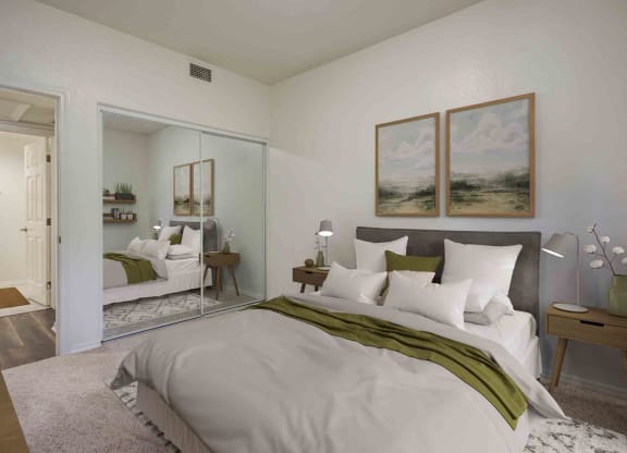 1 BR Apartments in Goleta CA - Sumida Gardens - Furnished Bedroom with Carpeted Flooring,  Large Bed, Two Nightstands with Lamps, Framed Wall Art, and Large Closet with Sliding Door Mirror